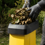 Bac de récupération rempli de copeaux de bois issus du broyage de végétaux avec des gants de protection